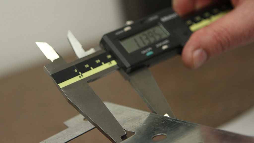 Quality inspection of custom metal enclosure with measurement tools on industrial workbench